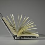 Laptop cradling an open book